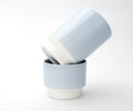 Two Asemi Hasami small cups in light blue stacked together, showing the soft glazed exterior and white base.