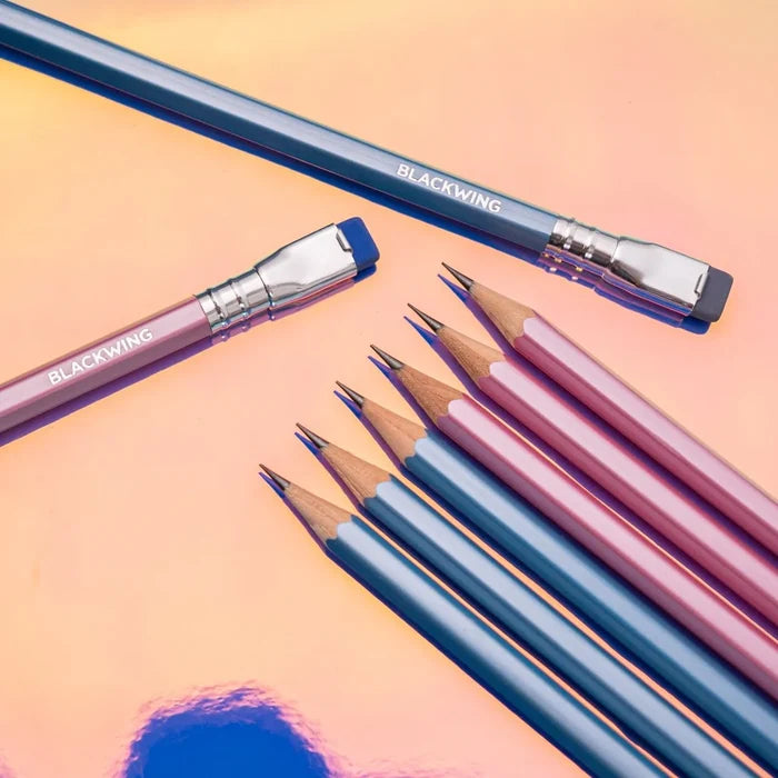 Assorted Blackwing pencils on a pastel background with sharpened graphite tips visible