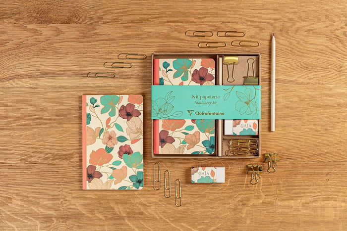 Gaïa Beige stationery items arranged on a wooden desk in a flatlay layout.