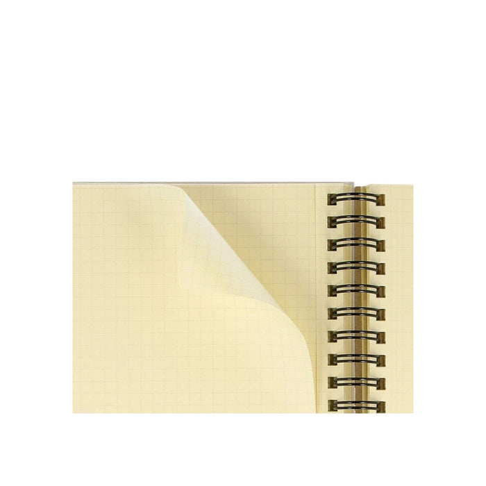 Detail of a page being turned in a Rollbahn notebook, showing cream grid paper and spiral binding.