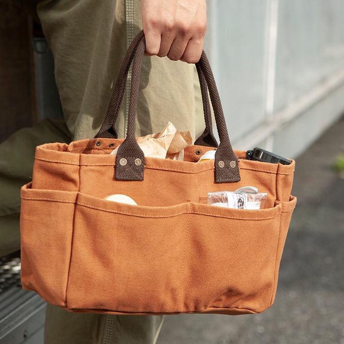 The Journal Shop - Person holding a brown Dulton Canvas Shoulder Tote Bag filled with everyday essentials.