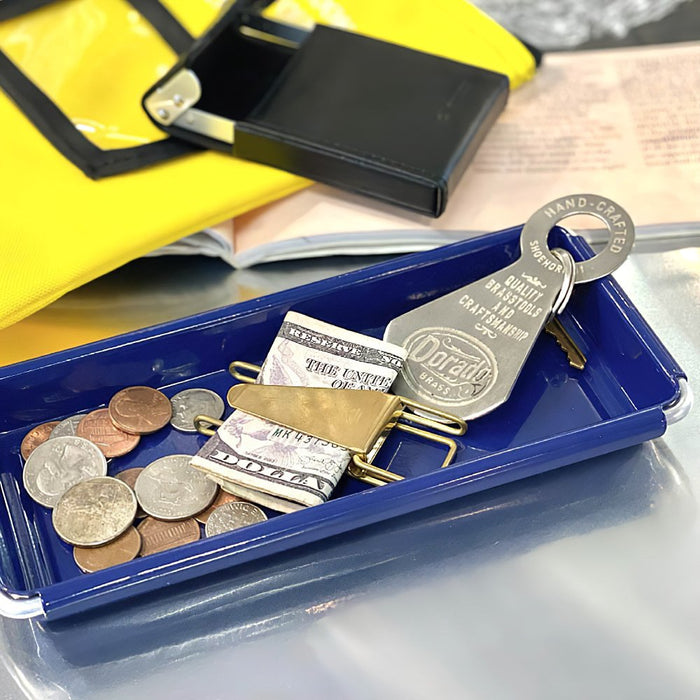 The Journal Shop - Navy Dulton Desktop Tray containing coins, clipped paper bill and key, placed on a silver table.