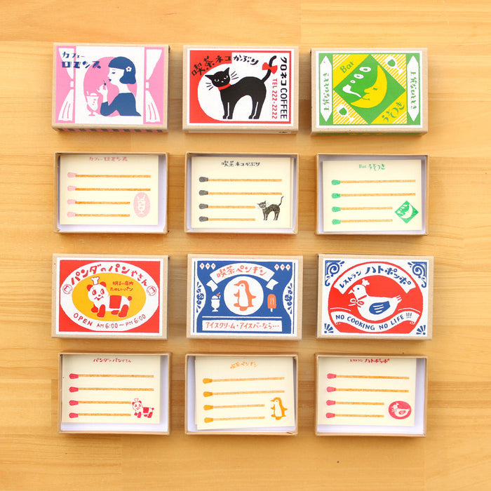 The Journal Shop - A collection of Furukawa Shiko Memo Pad Matchboxes arranged neatly on a wooden surface, featuring colourful vintage-style label designs.