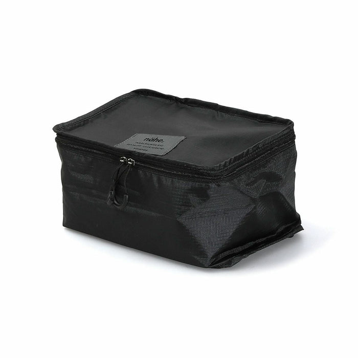 Side view of the black Nähe travel packing bag with zip closure and compact form.