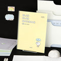 The Journal Shop - Iconic Blah Blah B5 Spiral Grid Notebook cream yellow cover displayed with black background and decorative items.