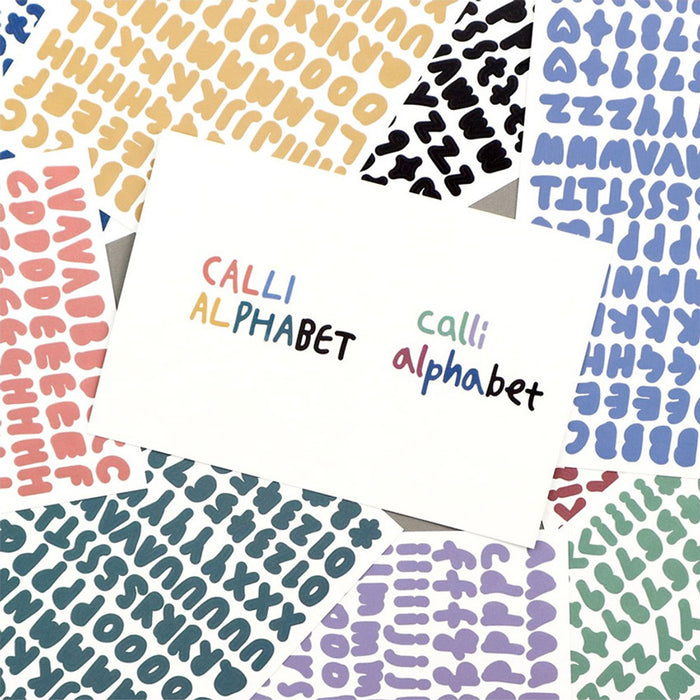 The Journal Shop - Close-up of gold Calli Alphabet Stickers arranged beside a white envelope and note card.