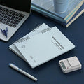 The Journal shop - Iconic Daily A5 Word Book vocabulary notebook in blue cover shown with pen and laptop.
