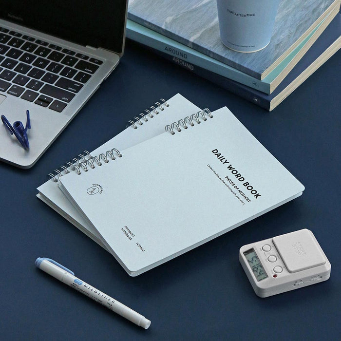 The Journal shop - Iconic Daily A5 Word Book vocabulary notebook in blue cover shown with pen and laptop.