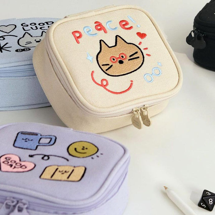 The Journal Shop - Close-up of cream and lavender Doodle Mini Pouches featuring playful doodle-style characters and text.
