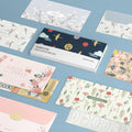 The Journal Shop - Collection of Iconic Fortune Envelopes in assorted floral and patterned designs displayed flat on a blue background.