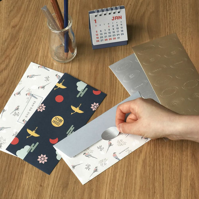 The Journal Shop - Navy and white patterned Iconic Fortune Envelopes placed beside a gold envelope opener on a wooden desk.