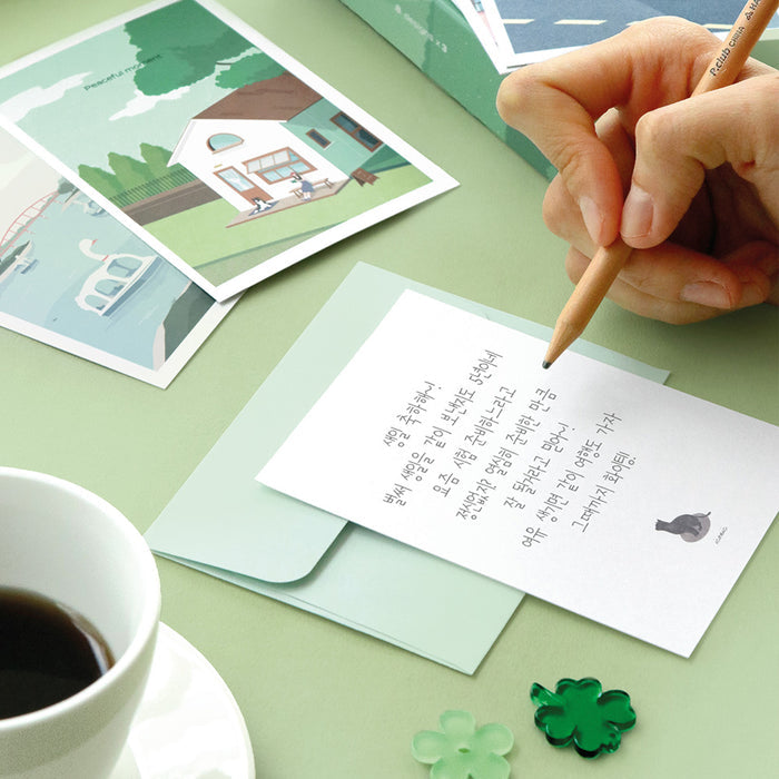 The Journal Shop - Person writing on Iconic Haru Message Card at desk with coffee and stationery beside.