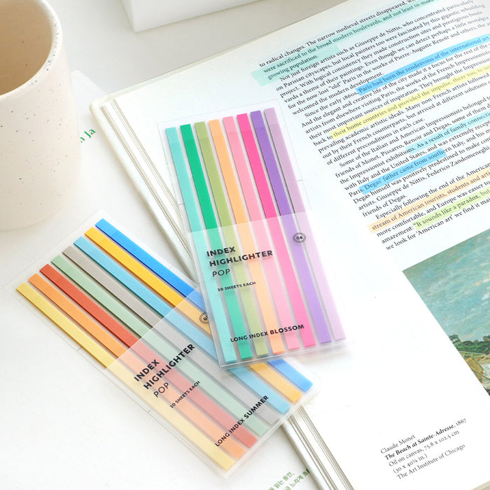 Brightly coloured Iconic Index Long Highlighter POP tabs laid out beside an open book.