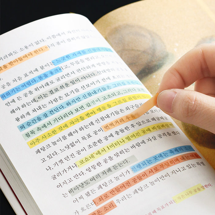 Hand highlighting text in a book using Iconic Index Long Highlighter POP strips.