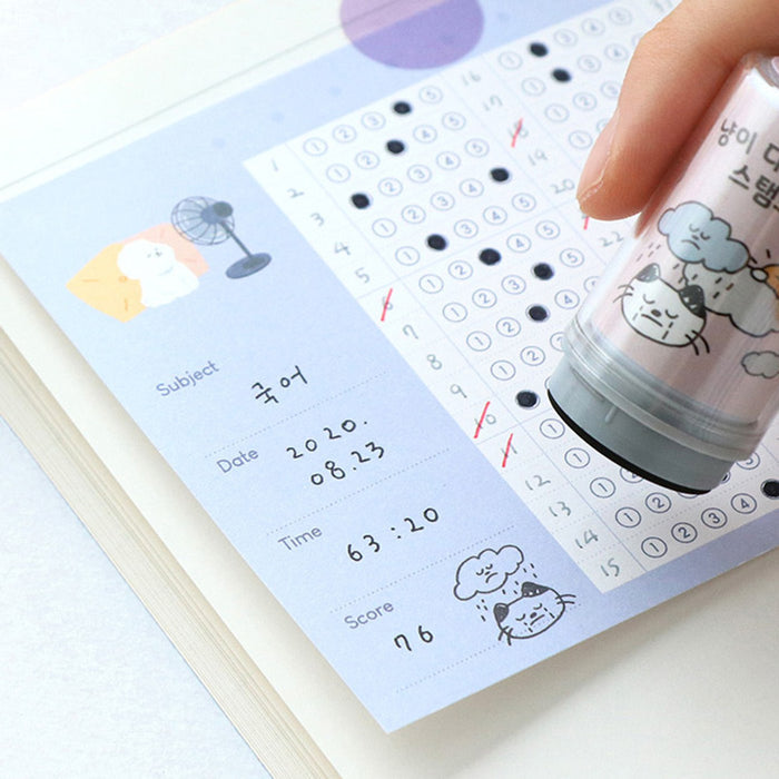 The Journal Shop - Hand using a Meow Self Inking Diary Stamp to decorate a planner with playful cat icons.