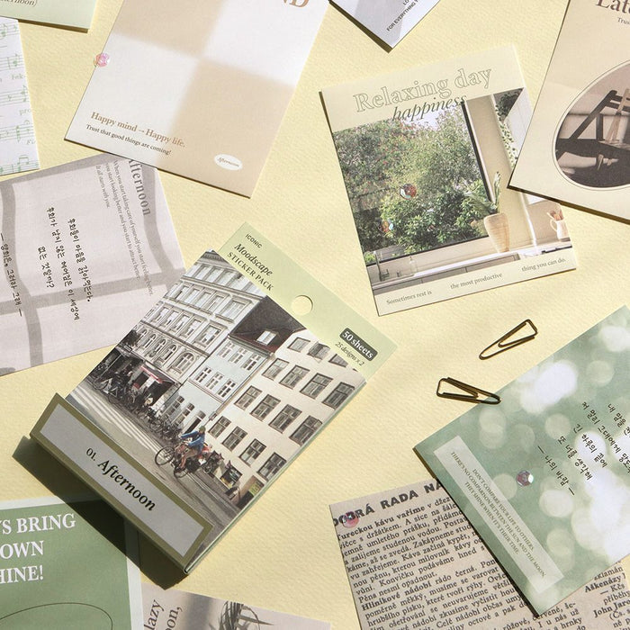 The Journal Shop - Sheets of Moodscape stickers with travel and cityscape designs spread out on a yellow desk.