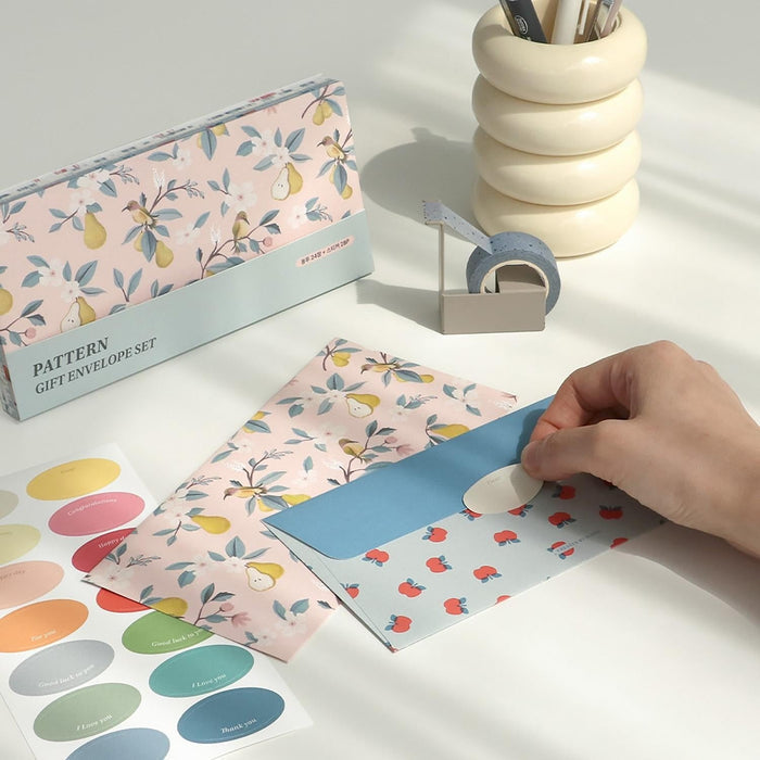 The Journal Shop - Hand sealing a blue and red patterned Iconic envelope with a cream sticker.