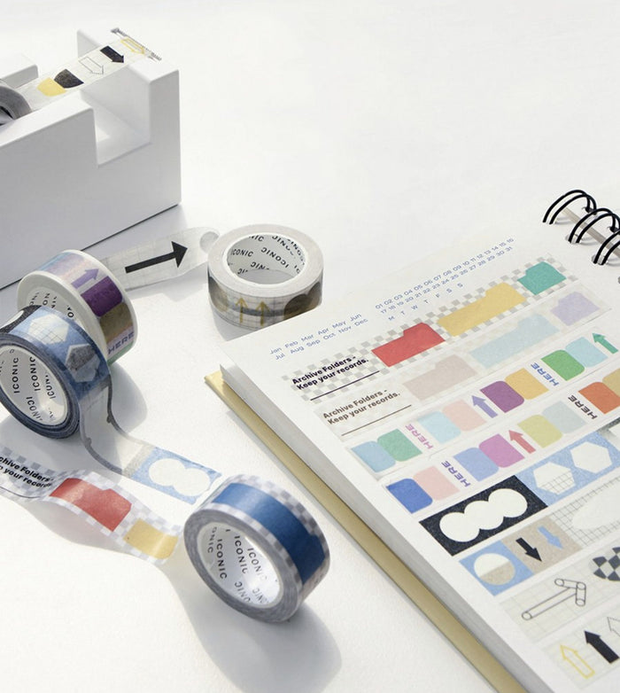 The Journal Shop - Several rolls of Iconic Shape Masking Tape displayed alongside a notebook and stationery, featuring assorted pastel and monochrome patterns.