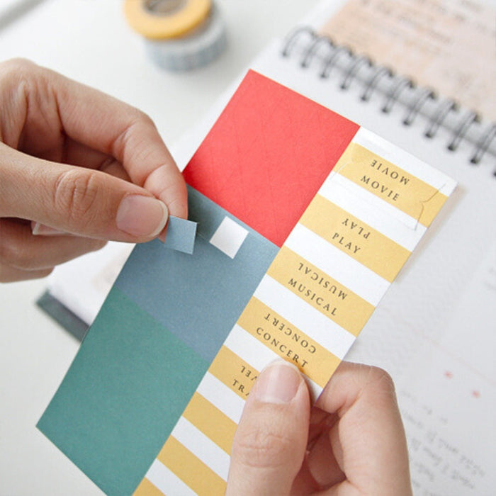 Person placing a colourful swatch card into a page of the Iconic Ticket Scrapbook Album.