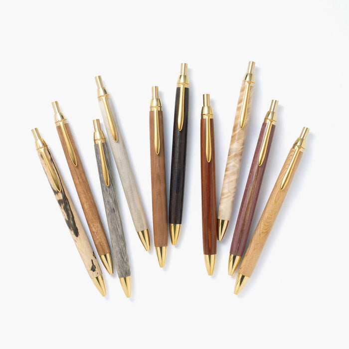 The Journal Shop - Assorted Kakimori Handcrafted Ballpoint Pens arranged in a fan shape, featuring a variety of polished wooden barrels with gold-toned clips and nibs.