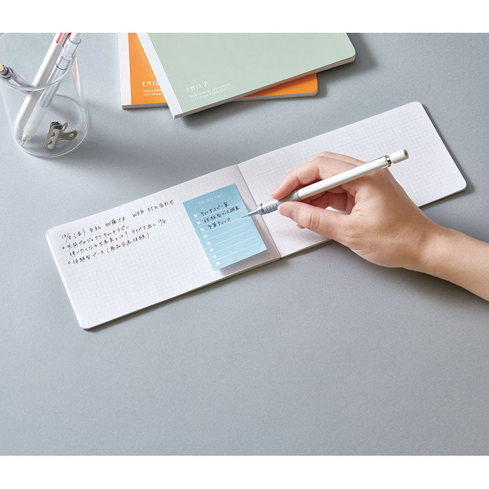 Writing notes inside an EMILY horizontal notebook on a clean desk.