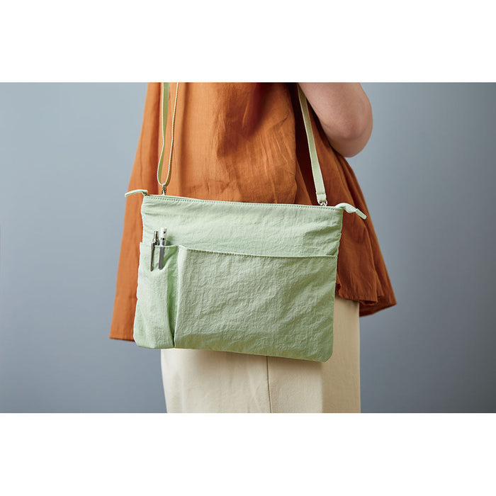 A5 Sage green EMILY work pouch worn crossbody, showing everyday carrying style.