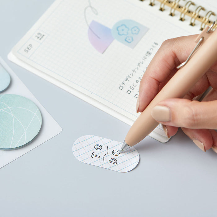 Hand peeling a HITOTOKI Coffret cosmetic sticky note from the pad.