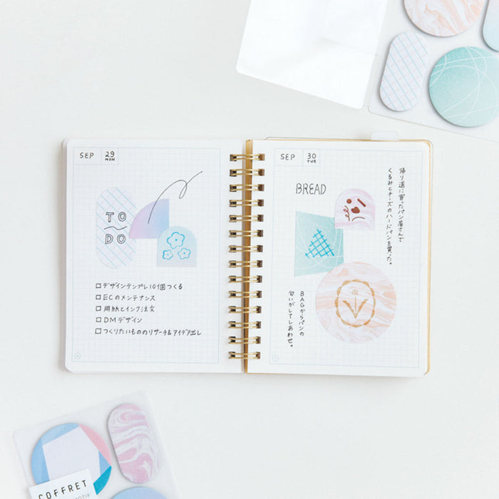 HITOTOKI Coffret cosmetic sticky notes used inside a notebook for page marking.