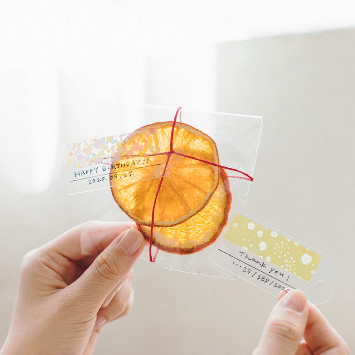 Hand applying KITTA clear washi sticker to paper for journalling or decoration.