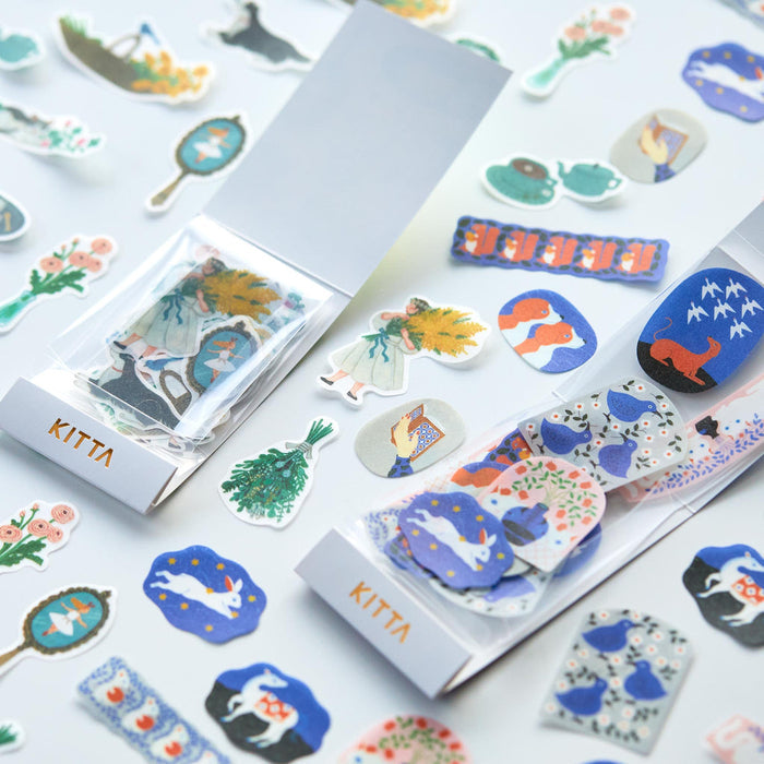Assorted KITTA flake washi stickers displayed on paper in a flat lay arrangement.