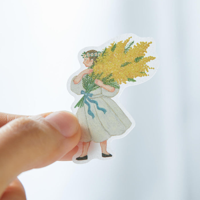 Hand holding a single KITTA flake washi sticker to show scale.