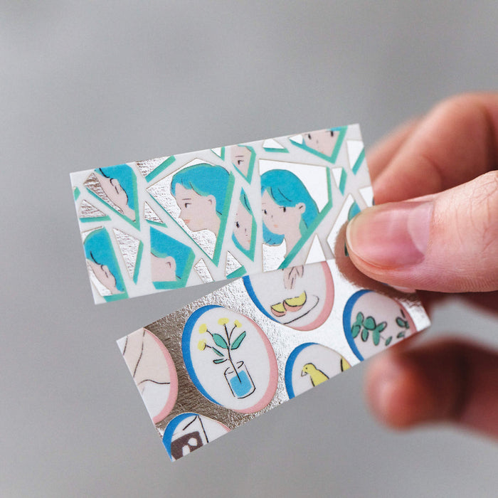 Hand holding a strip of KITTA wide geometric washi sticker, showing flexibility and pattern detail.
