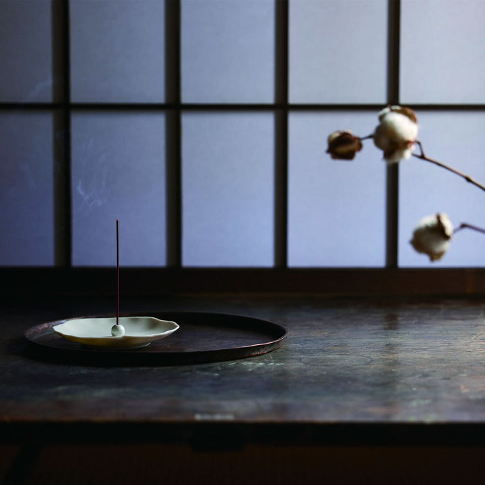 Kousaido Ika-Denshin incense burning on a ceramic stand in a calm Japanese-style interior.