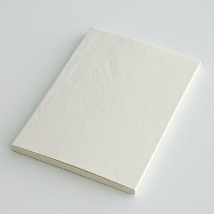 Angled view of Midori MD Paper Notebook A5 Grid, slim design with flexible cream cover.