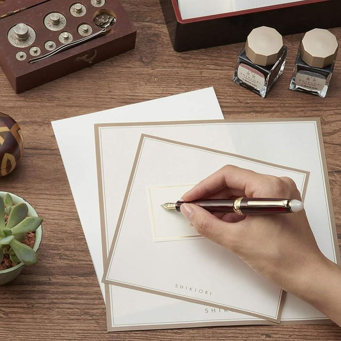 Sailor Shikiori Night Burn fountain pen in use, writing on cream stationery.