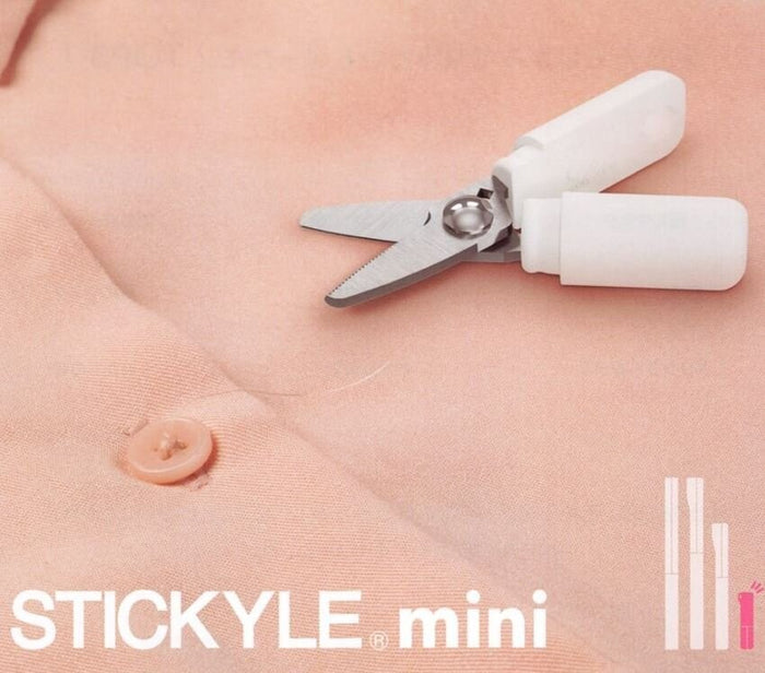Sun-Star Stickyle ultra-compact mini scissors in white, shown cutting a loose thread on fabric.