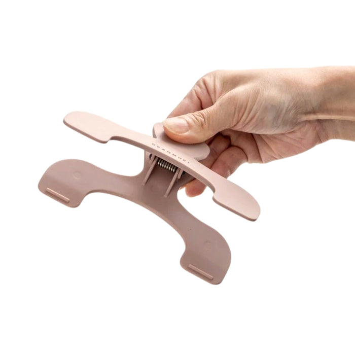 Hand holding the Sun-Star Ukanmuri Clip in peach beige, showing the spring mechanism and underside design.