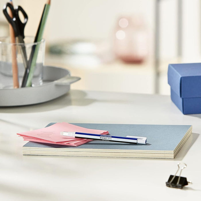 Tombow MONO Zero square retractable eraser placed on a desk alongside stationery tools.