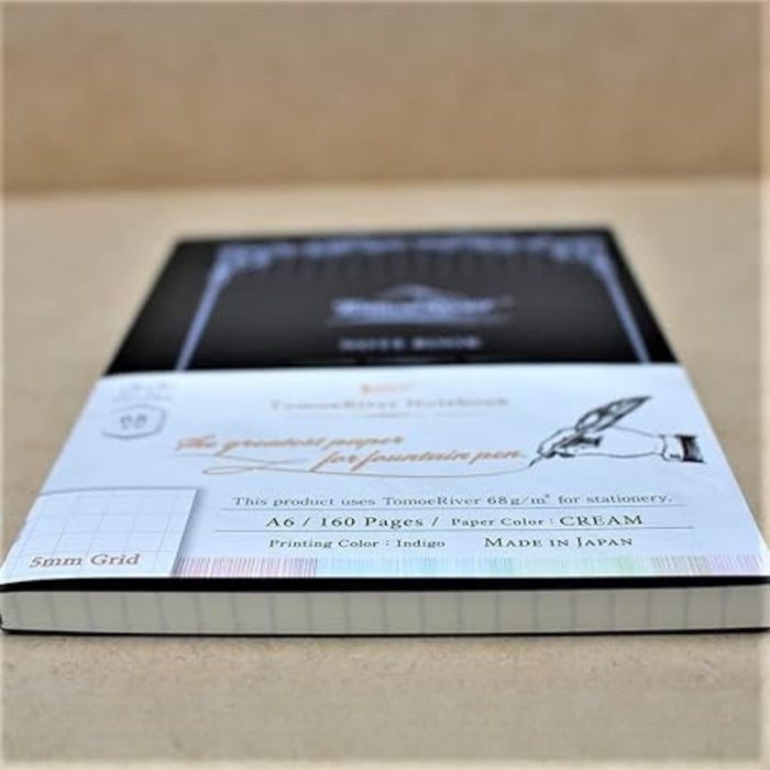 Flatlay of Tomoe River A6 squared notebook with decorative border design.