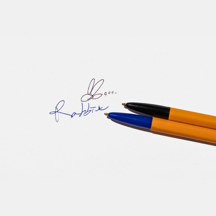 Hand holding the Tools To Live By dual-tip ballpoint pen during writing.