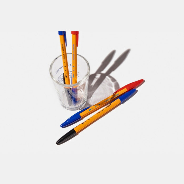 Tools To Live By dual-tip ballpoint pen arranged with stationery on a desk.