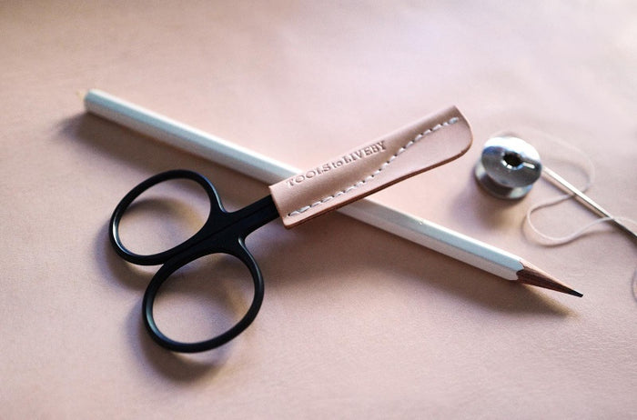 Leather pencil caps by Tools to Live By displayed with scissors on desk.