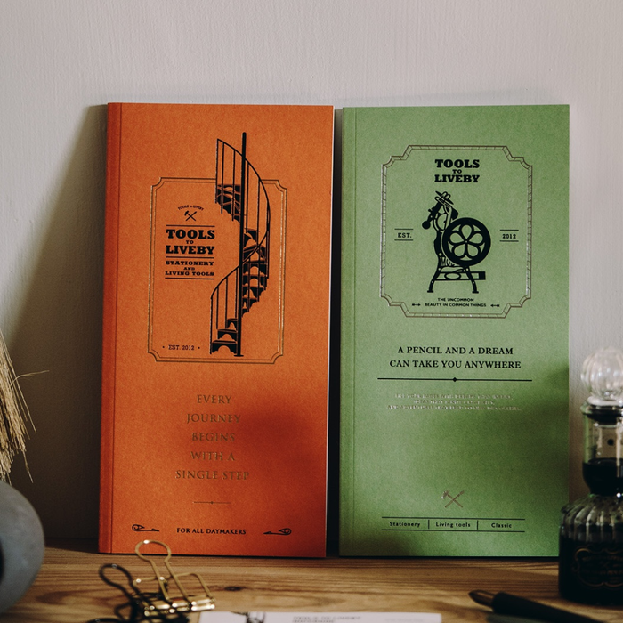 Tools To Live By Spiral Staircase Grid Notebook in orange and green shown together