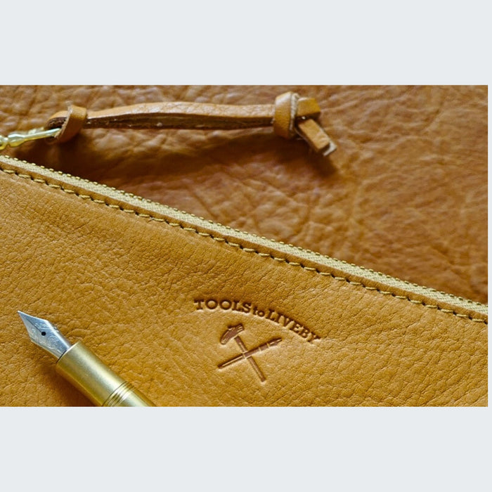 Tan (M) - Close-up of the embossed logo on a tan Tools To Live By leather pen case.
