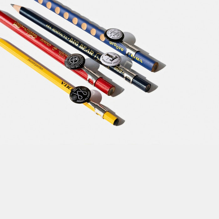 Tools To Live By pencil topper pocket clips on pencils displayed in white surface.