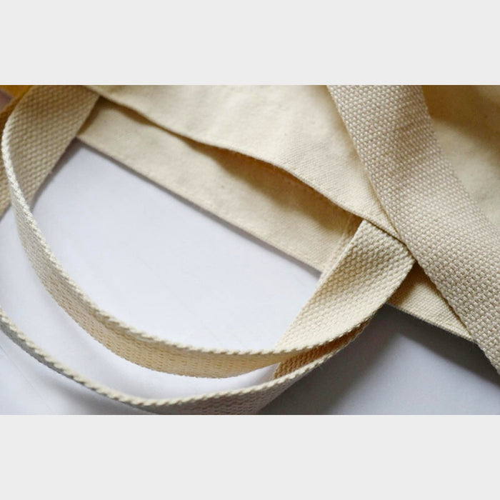 Close-up of handles on beige Tools To Live By canvas tote bag.
