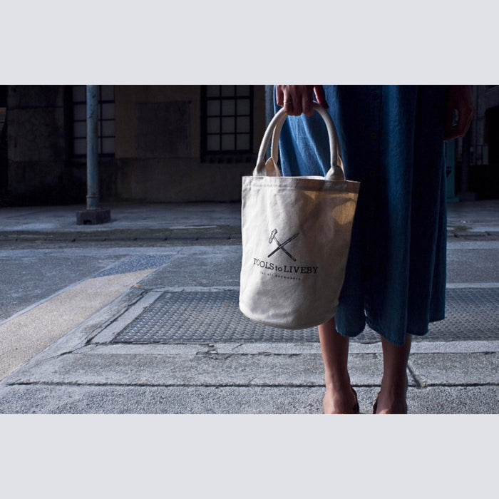 Tools To Live By cream tote bag worn outdoors, showing everyday lifestyle use.
