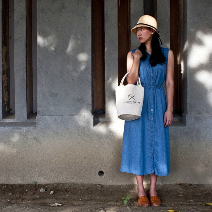 Model carrying the Tools To Live By cream canvas tote bag as a shoulder bag.