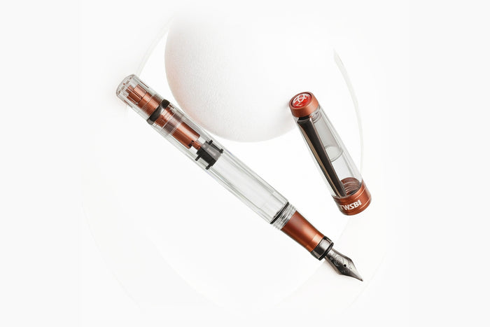 Close-up of a TWSBI Diamond 580 fountain pen with copper aluminium accents, cap removed, placed on a white background.