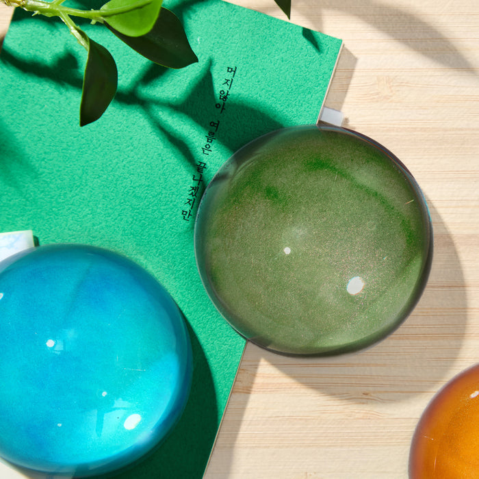 Close-up of blue and green Wearingeul crystal ink paper weight with glossy finish.